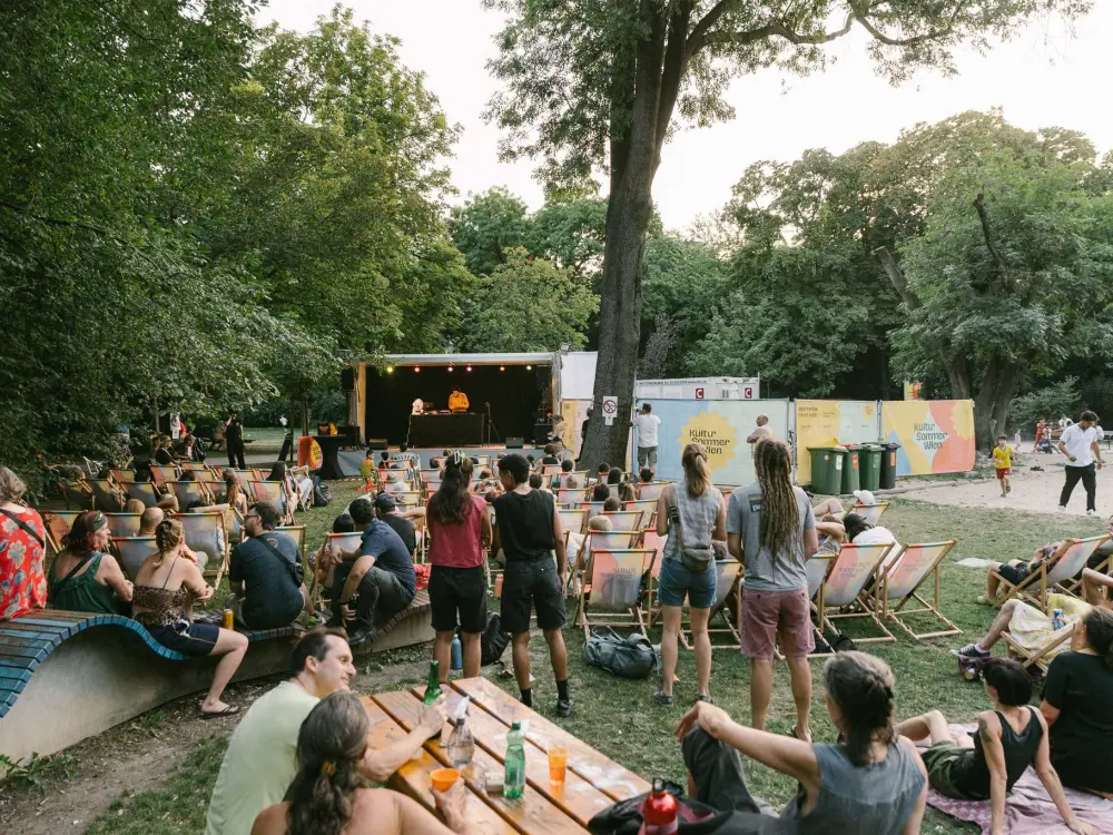 Kimyan: Kimyan performt auf der Kultursommer-Bühne im Waldmüllerpark. Der Park ist gut gefüllt, viele Menschen hören dem Konzert zu.