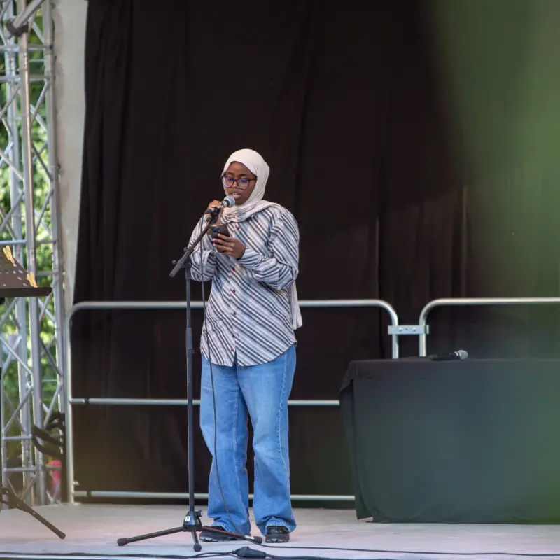 Munira Mohamud: Munira Mohamud steht auf der Kultursommer-Bühne vor einem Standmikrofon und performt einen Text.