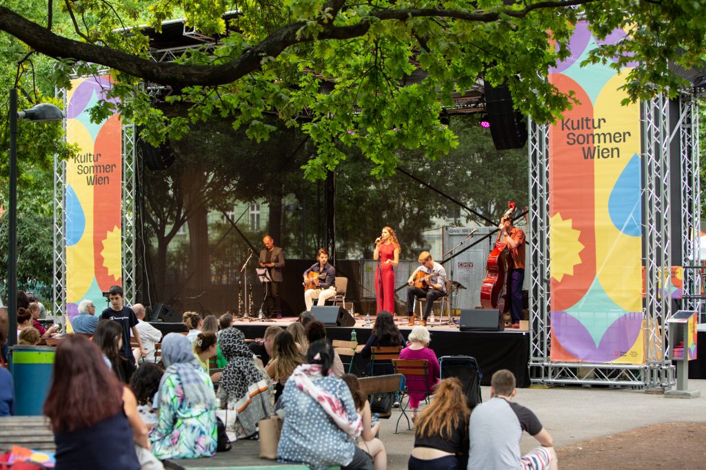 Blick auf die Bühne im Mortarapark. Auf der Bühne spielt Belle Affaire ein Konzert im Rahmen des Kultursommer Wien 2022.