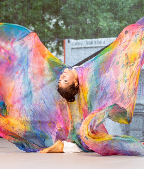 Künstlerin auf der Bühne tanzt mit farbenfrohem Tuch