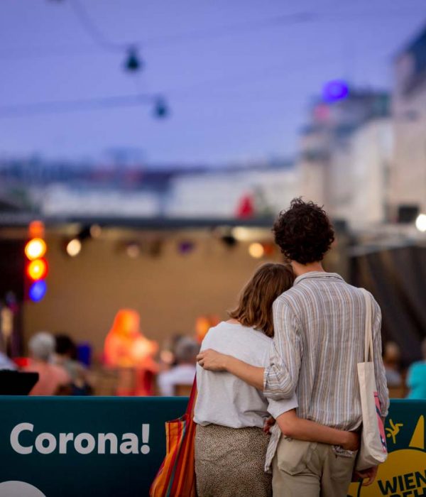 Ein Mann und eine Frau umarmen sich und blicken auf eine Bühne